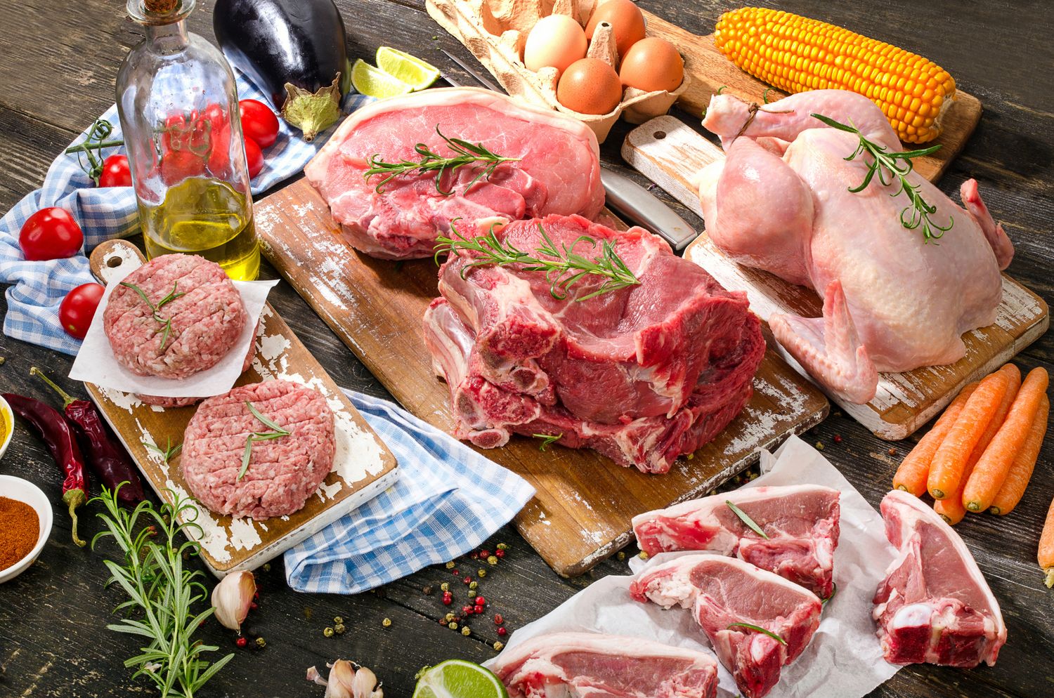 Different types of fresh raw meat with vegetables and herbs on wooden background. View from above